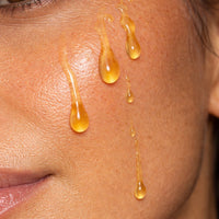 Close-up of honey coloured face oil droplets on skin