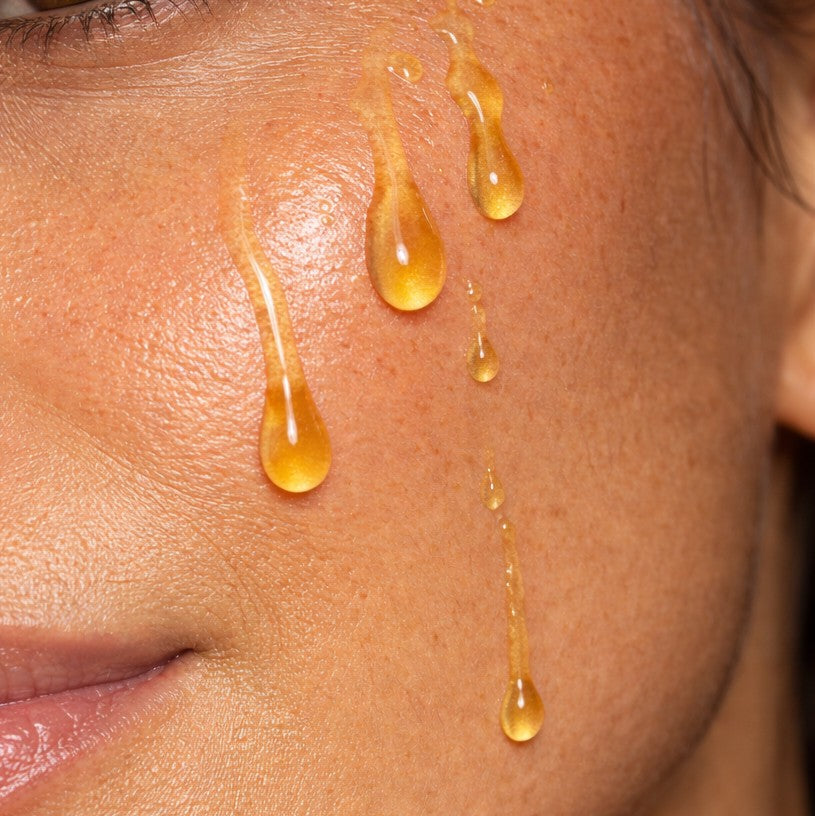 Close-up of honey coloured face oil droplets on skin